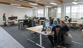 Employees work at their desks in an open-plan office.