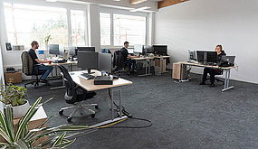 Employees work in an open-plan office.