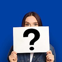 Woman holds a sign with a question mark in front of her face.