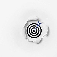 A target with an arrow in the center, visible through a torn piece of paper.
