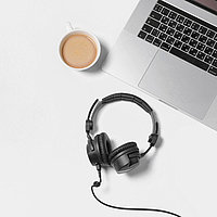 Laptop, schwarze Headset-Kopfhörer und Kaffeetasse auf weißem Tisch