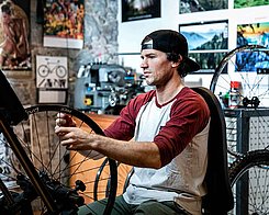 Man in a baseball cap working on his bicycle.