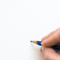 Hand hält blauen Stift und schreibt auf weißem Papier
