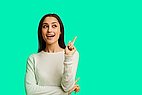 Woman stands in front of a green background and raises her index finger.