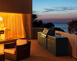 Outdoorküche auf einer Terasse und im Hintergrund ist ein Sonnenuntergang