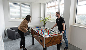 Two employees play at the jigsaw table.