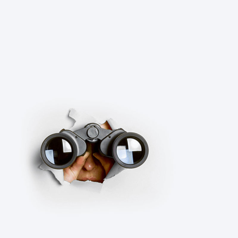 Person looking through binoculars out of a hole in a white wall