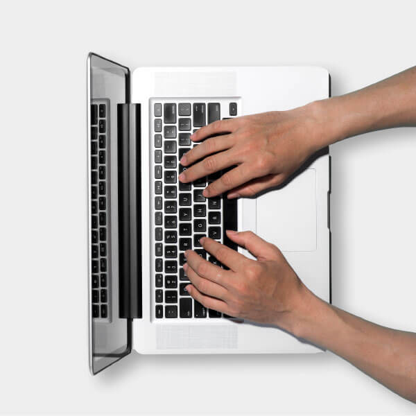 Two hands typing on a laptop seen from above