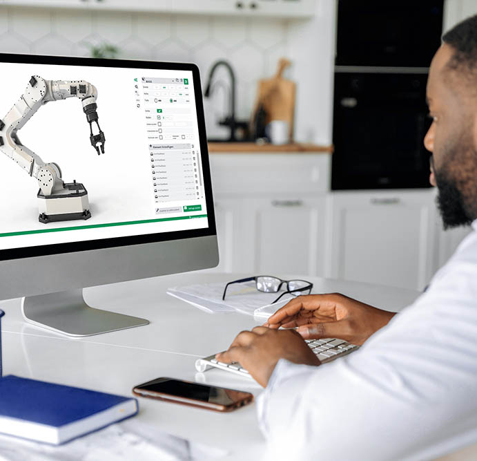 Mann sitzt am Computer und bedient eine Software zur Steuerung eines Roboterarms, der auf dem Bildschirm dargestellt ist.
